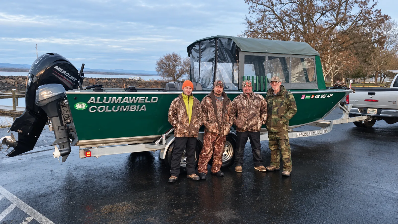 Green Alumaweld Columbia with a canopy cabin on its trailer at a launch ramp, four anglers standing in front