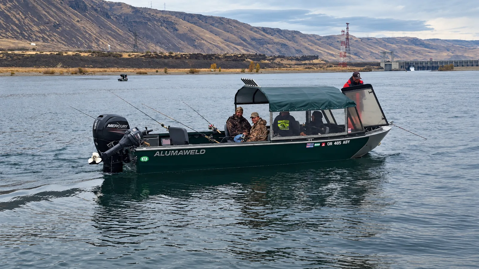 Alumaweld guide boat with a canopy and rod holders running on the river, anglers aboard