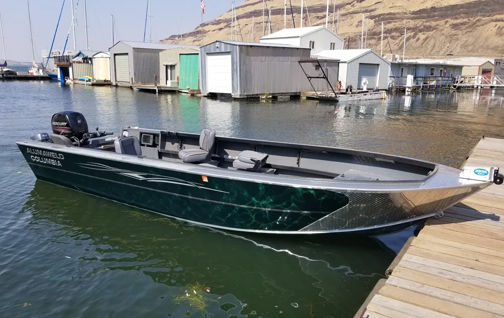 Dark green Alumaweld Columbia aluminium boat tied at a floating dock with a marina behind it