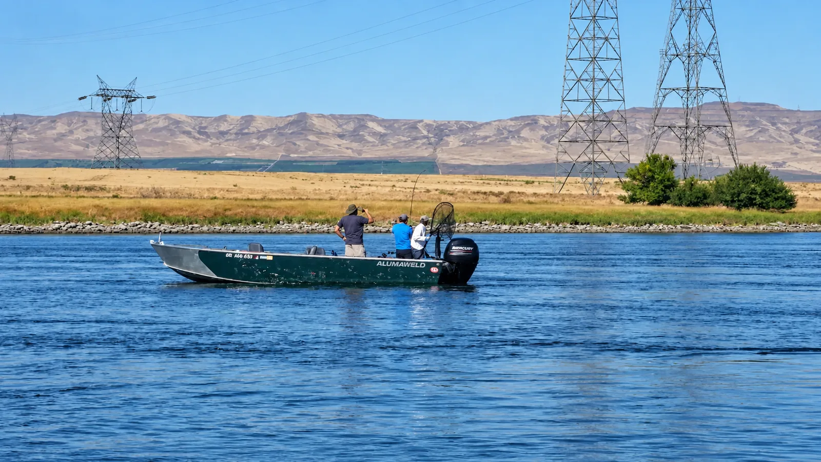 Open Alumaweld guide boat with three anglers and a landing net on the river