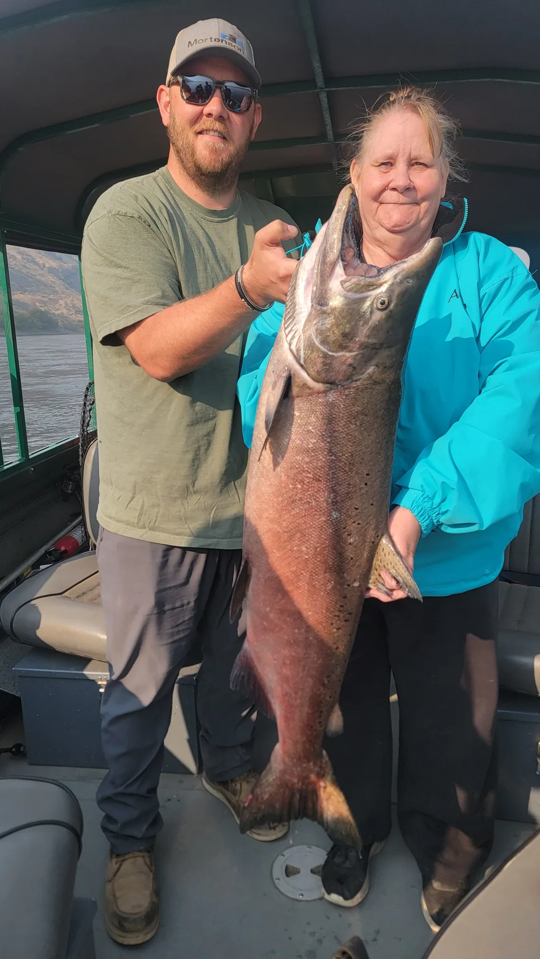 Couple on the boat holding a big king salmon