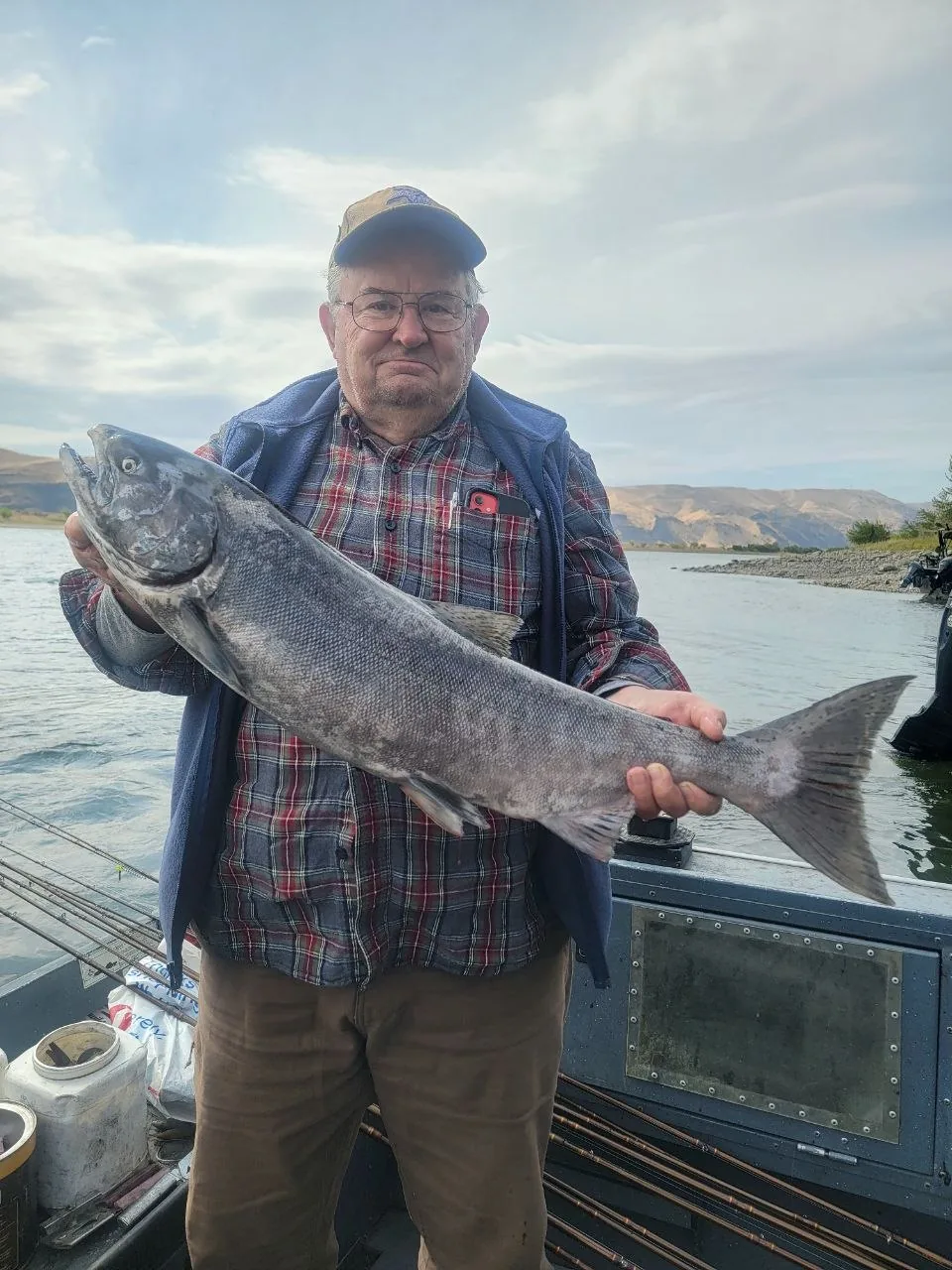 Angler in a plaid shirt holding a big Chinook salmon