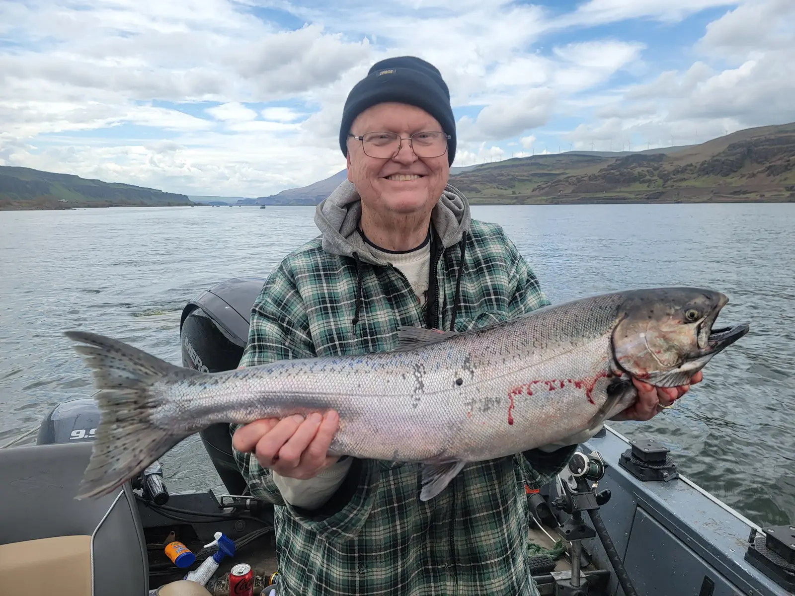 Smiling angler in a plaid jacket holding a large Chinook salmon