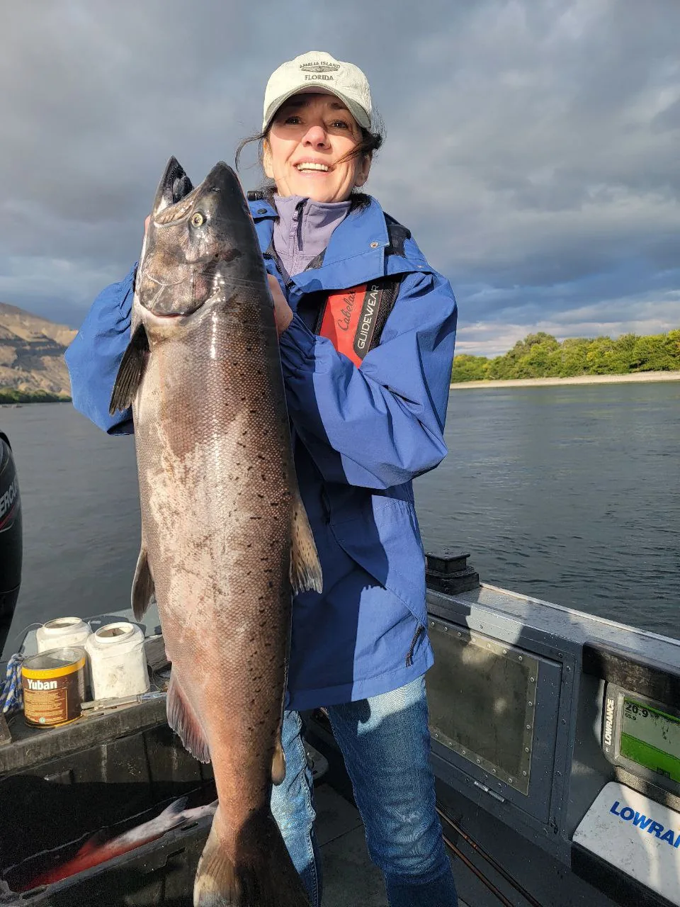 Woman in a blue jacket holding a big Chinook salmon