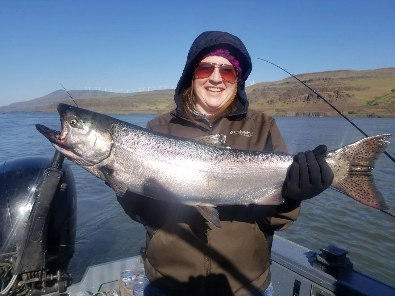 Woman in a hooded jacket holding a Chinook salmon on the boat