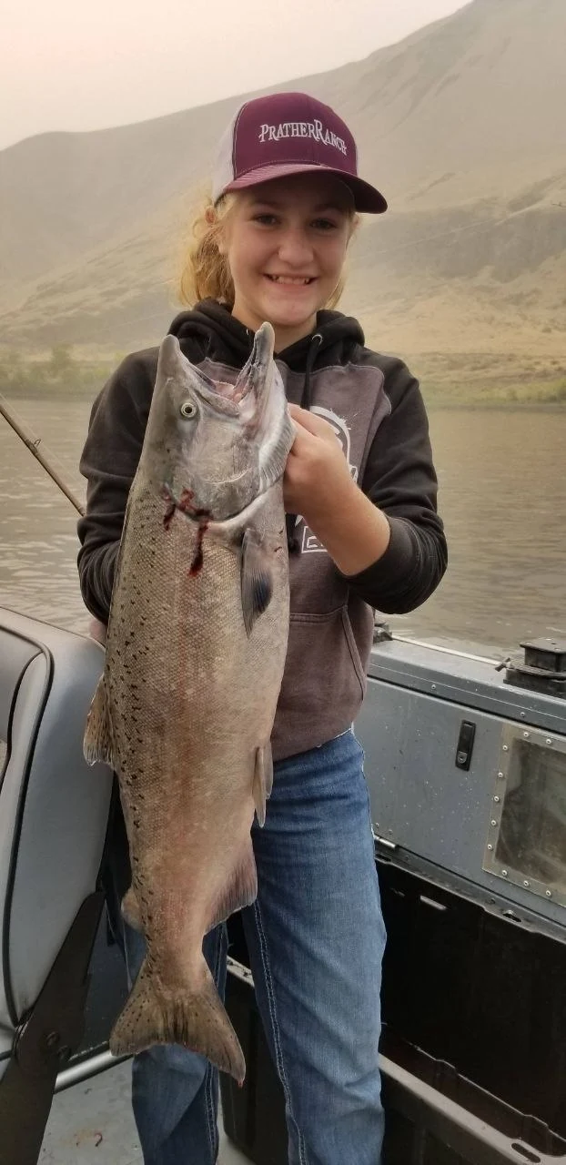 Young angler in a maroon cap holding a fall Chinook salmon