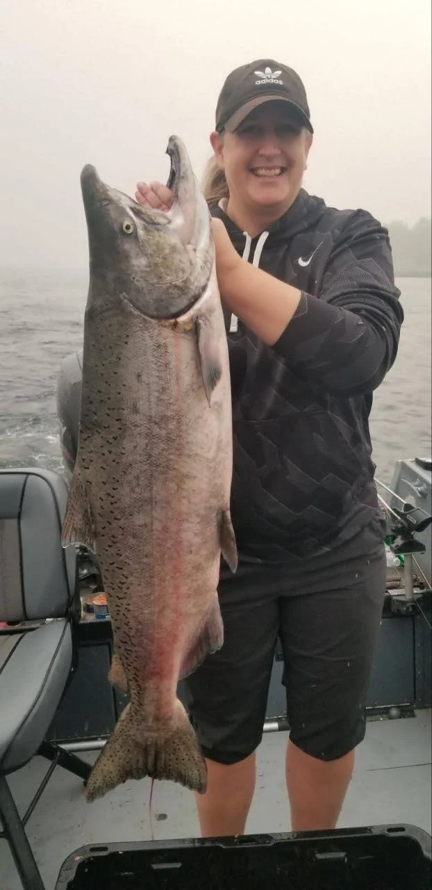 Woman in a dark hoodie holding a fall Chinook salmon