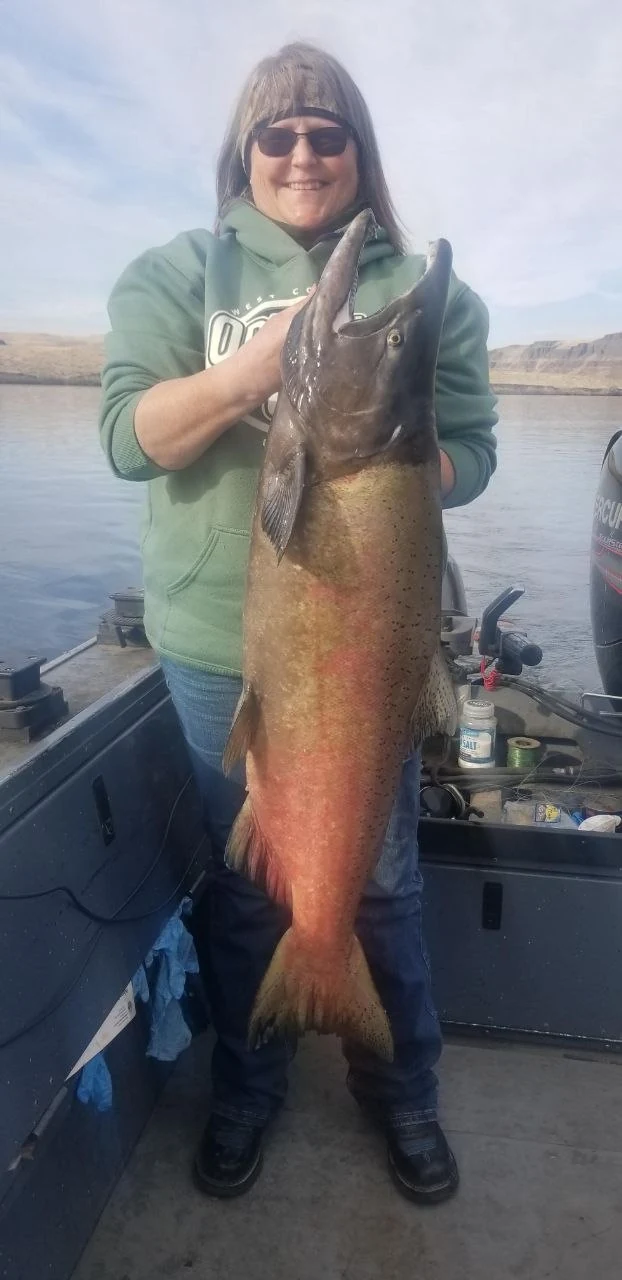 Angler in a green jacket holding a Hanford Reach fall Chinook