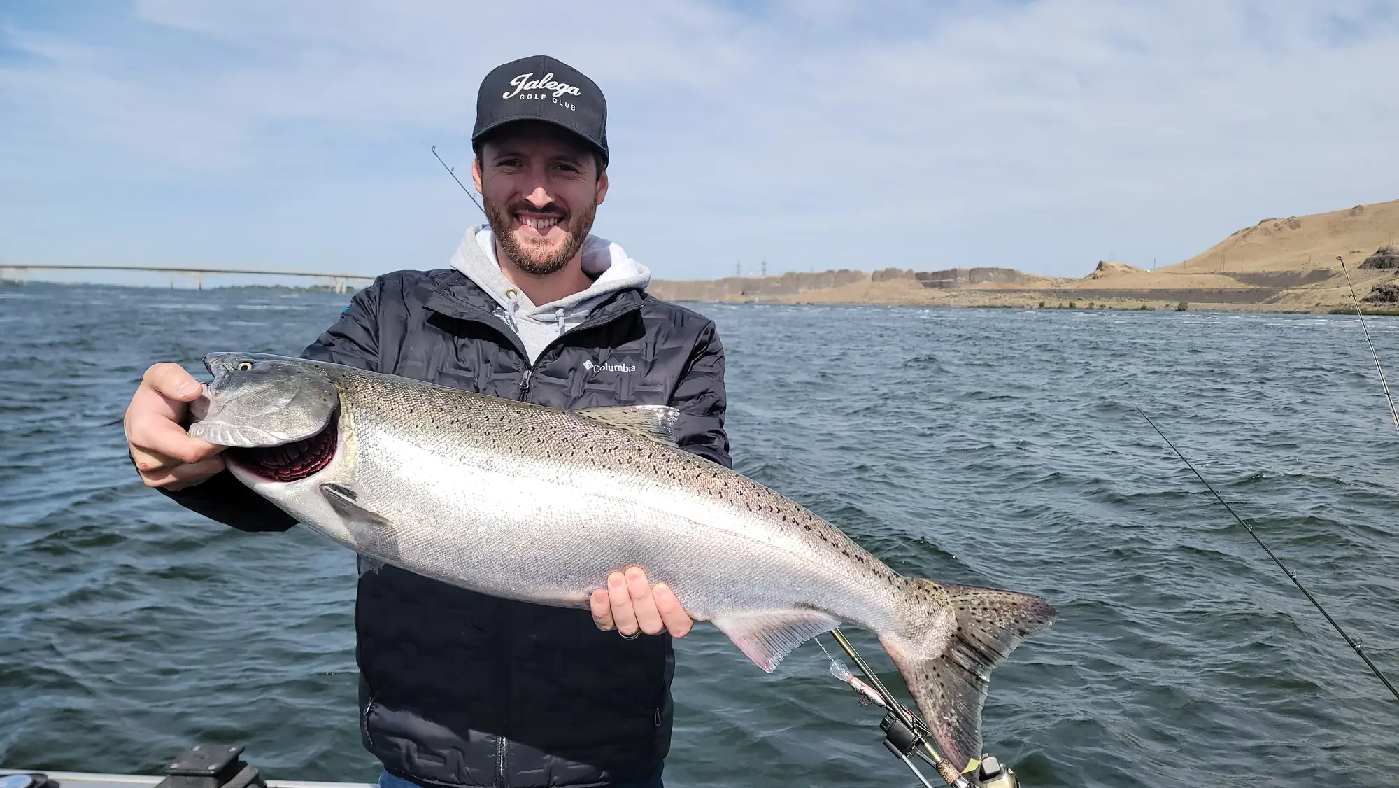 Smiling angler holding a fresh silver Chinook on the river