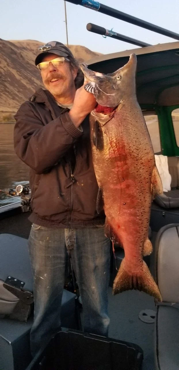 Angler holding a big red spawning Chinook salmon inside the boat