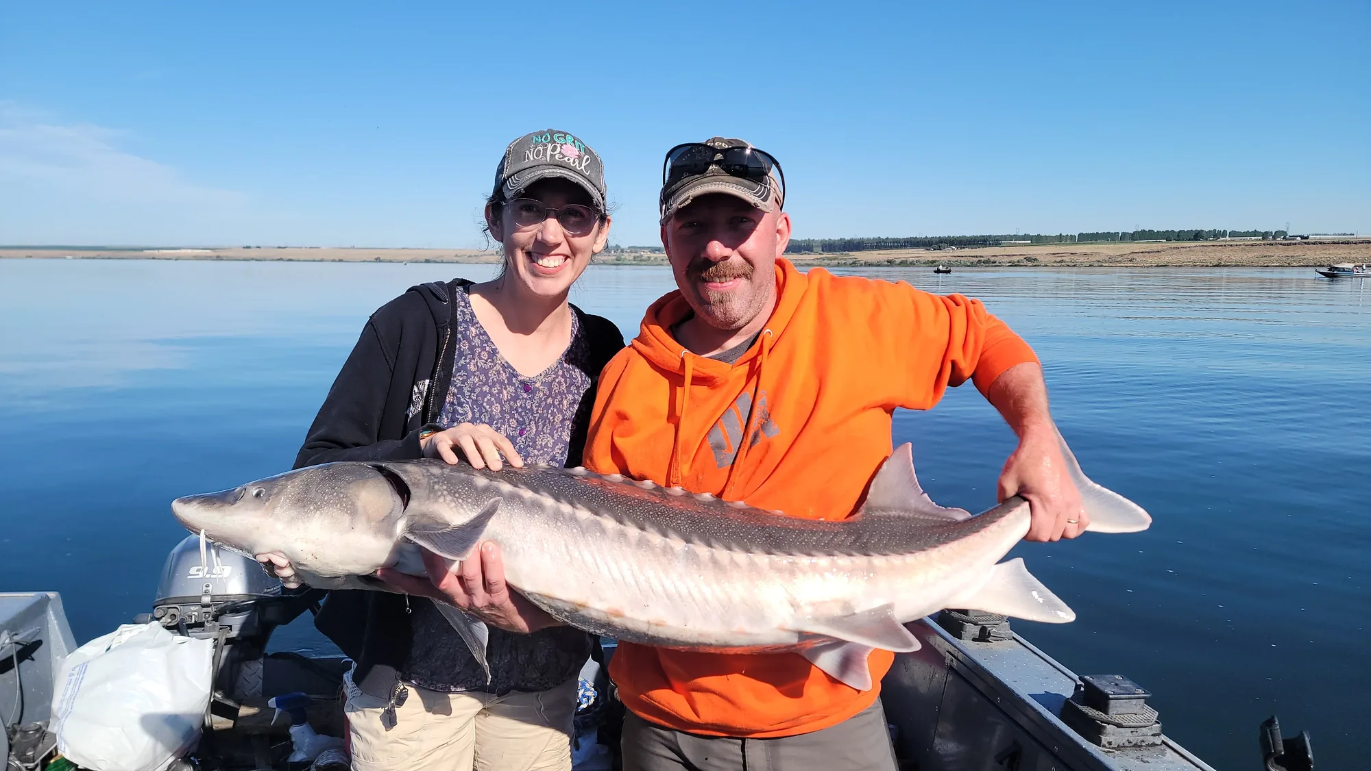 Couple on the boat holding a keeper sturgeon between them
