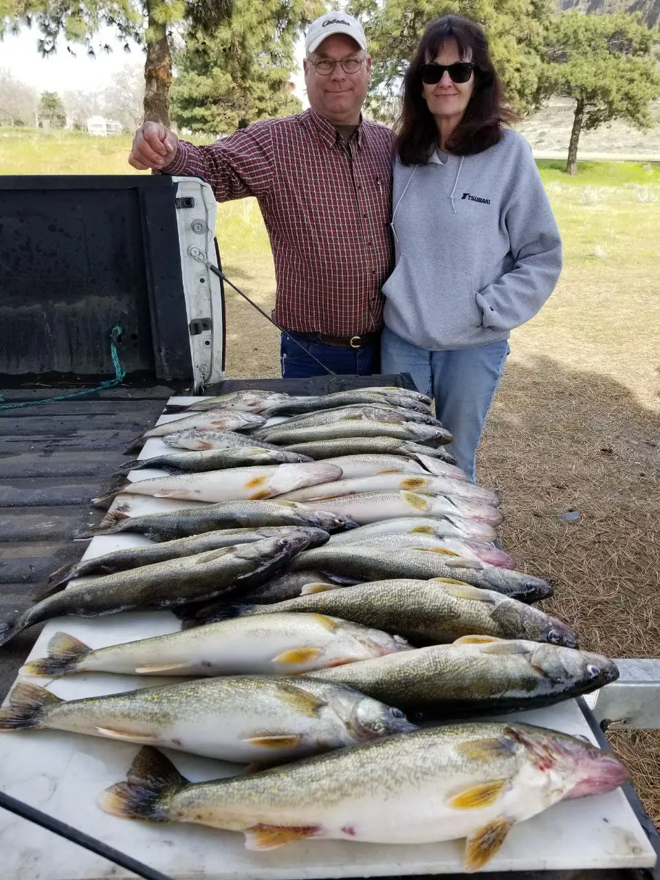 Couple smiling behind a long table of walleye