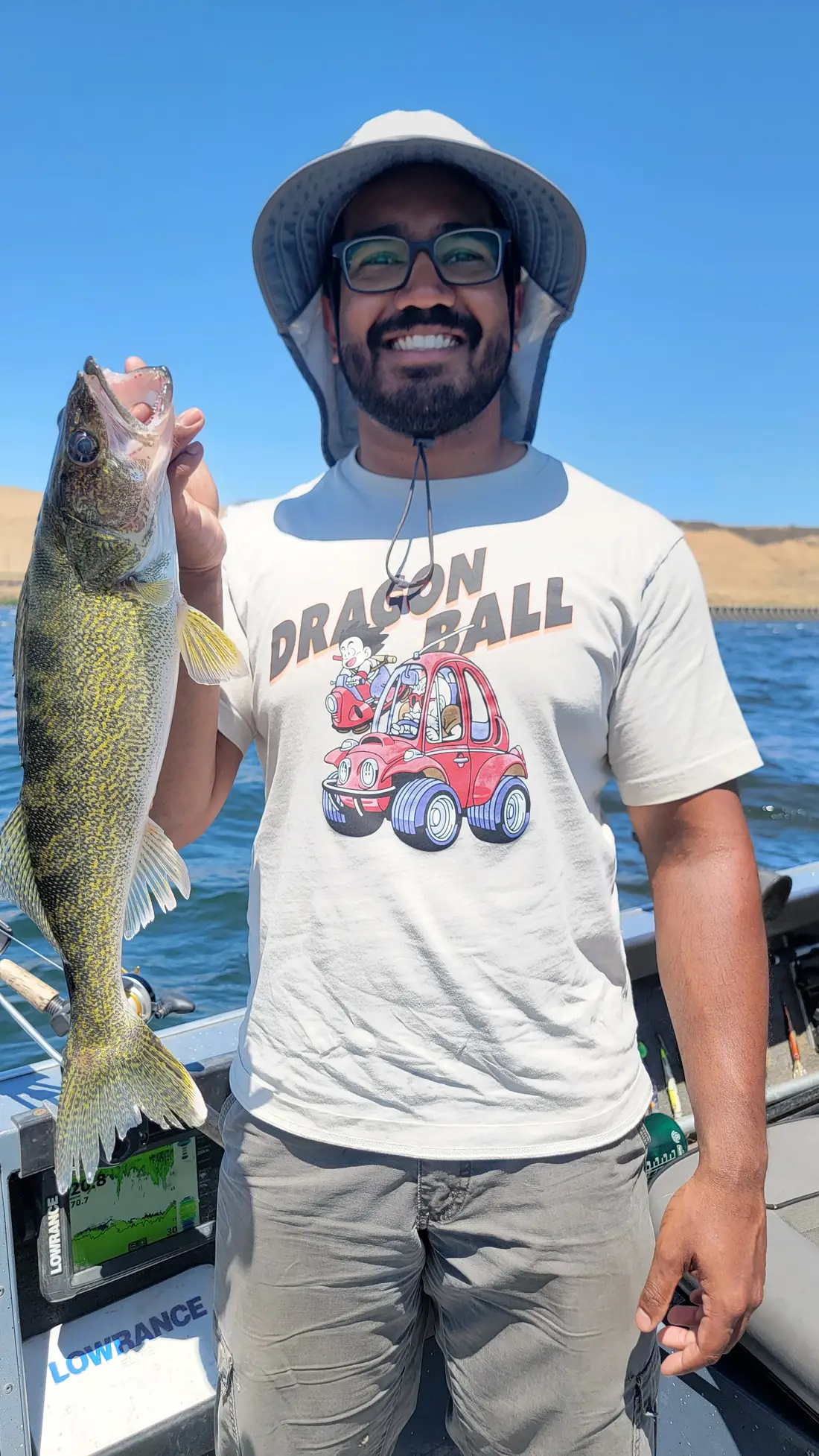 Angler in a sun hat standing on the boat holding an upright walleye
